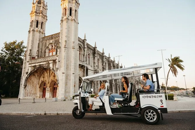 A white tuk-tuk parked in front of the Jerónimos Monastery